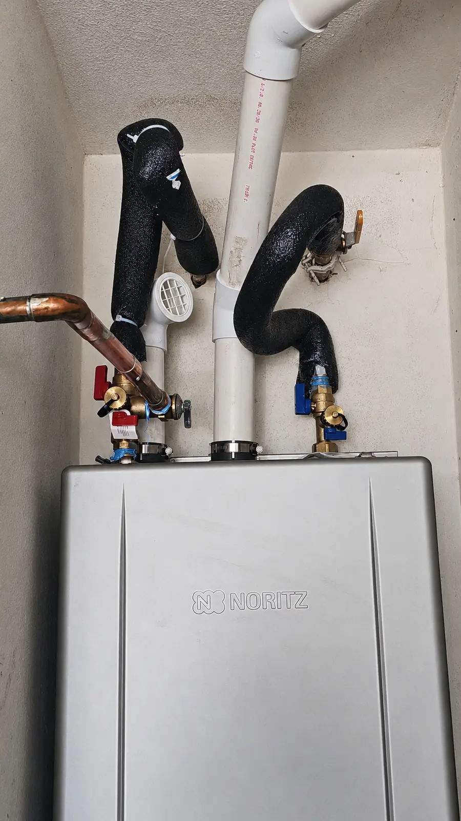 Close-up of tankless water heater valves and insulated connections
